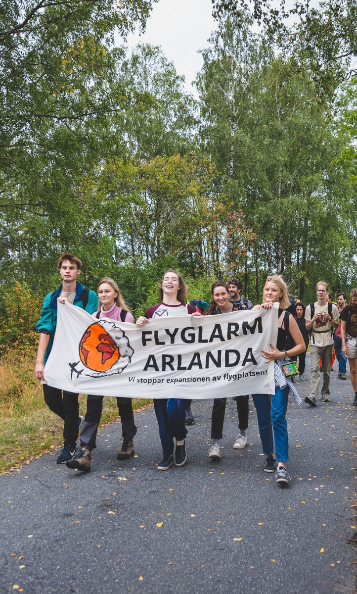 Protesters from Flyglarm Arlanda group walking with banner