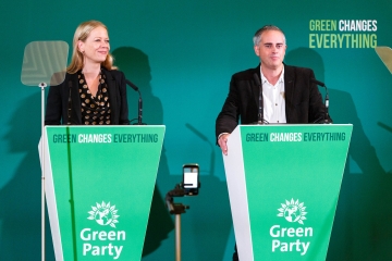 Sian Berry and Jonathan Bartley standing at green podiums